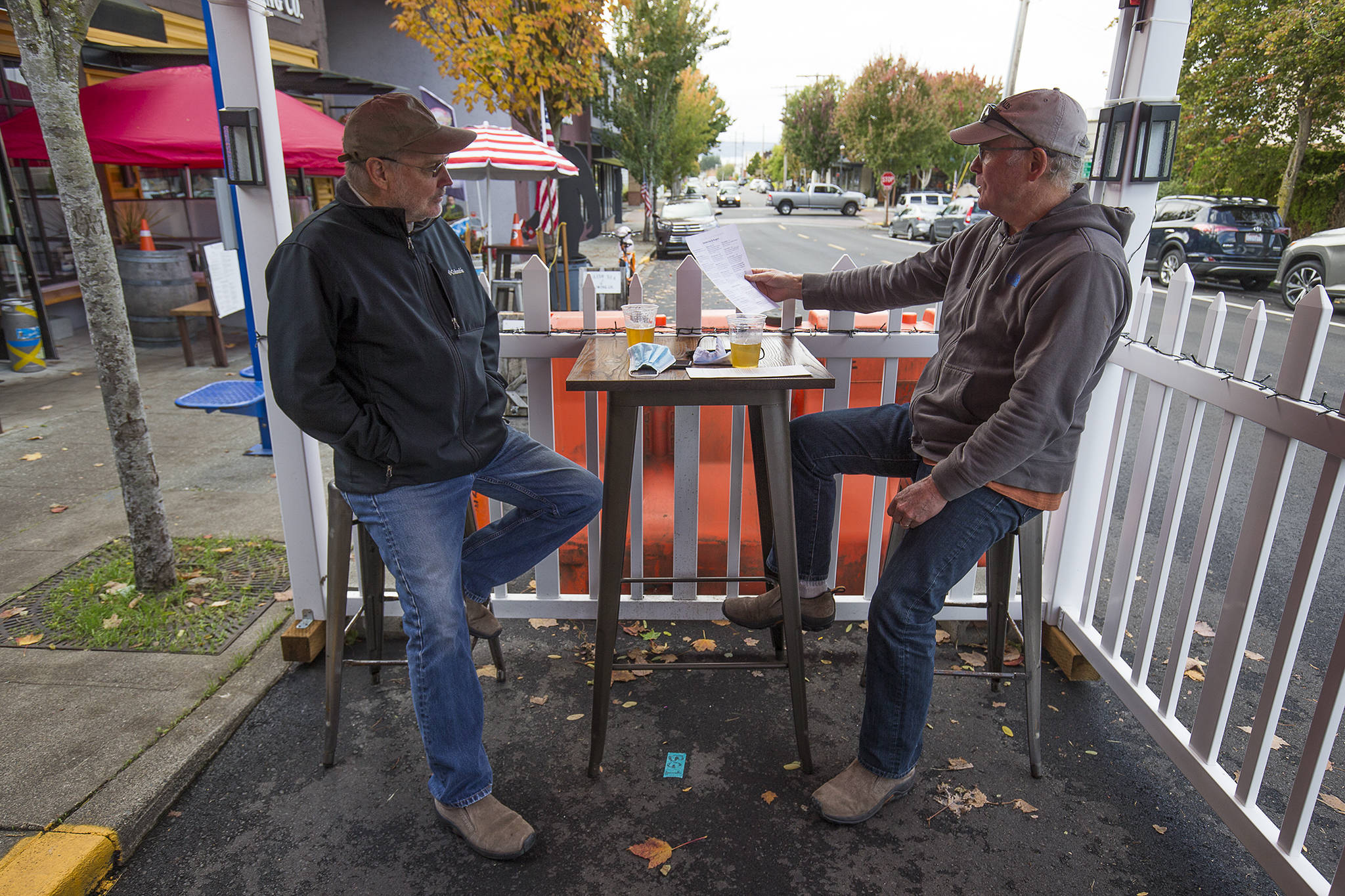 Scott McEntire and Jim Coe enjoy a drink and lunch in an outdoor seating tent at the Salish Sea Brewing Co. on Dayton Street in Edmonds on Monday. (Andy Bronson / The Herald)