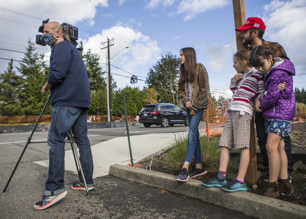 Television crews and onlookers watch as a carjacking suspect makes his way down a ladder on Wednesday near Mill Creek. (Olivia Vanni / The Herald)
