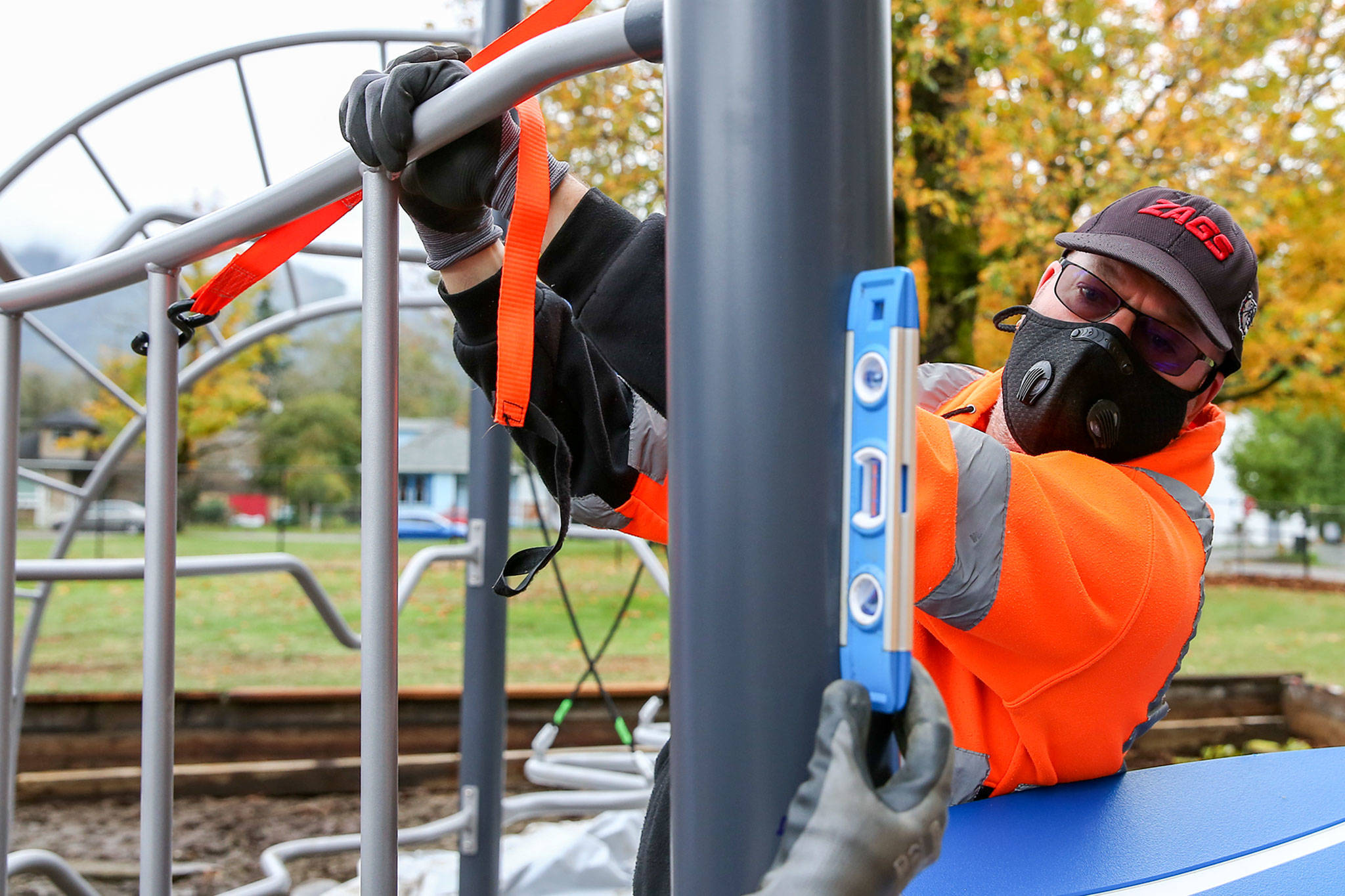 Tony Hallmark checks plumb while installing playground equipment Saturday afternoon at Gold Bar Elementary School in Gold Bar. (Kevin Clark / The Herald)