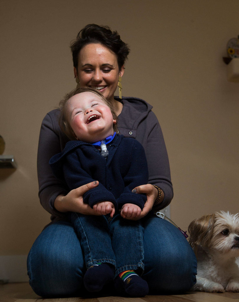 Malachi Stohr, 2, laughs as his mother Whitney sings the “Llama Song” at home Oct. 21 in Lynnwood. Stohr was born with spina bifida. He has spent much of his life at Seattle Children’s Hospital. (Andy Bronson / The Herald)
