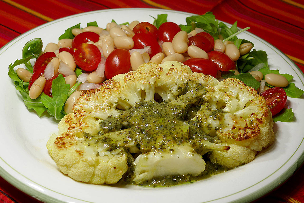 Roasted cauliflower steak topped with pesto sauce pairs well with a bean and tomato salad. (Linda Gassenheimer)
