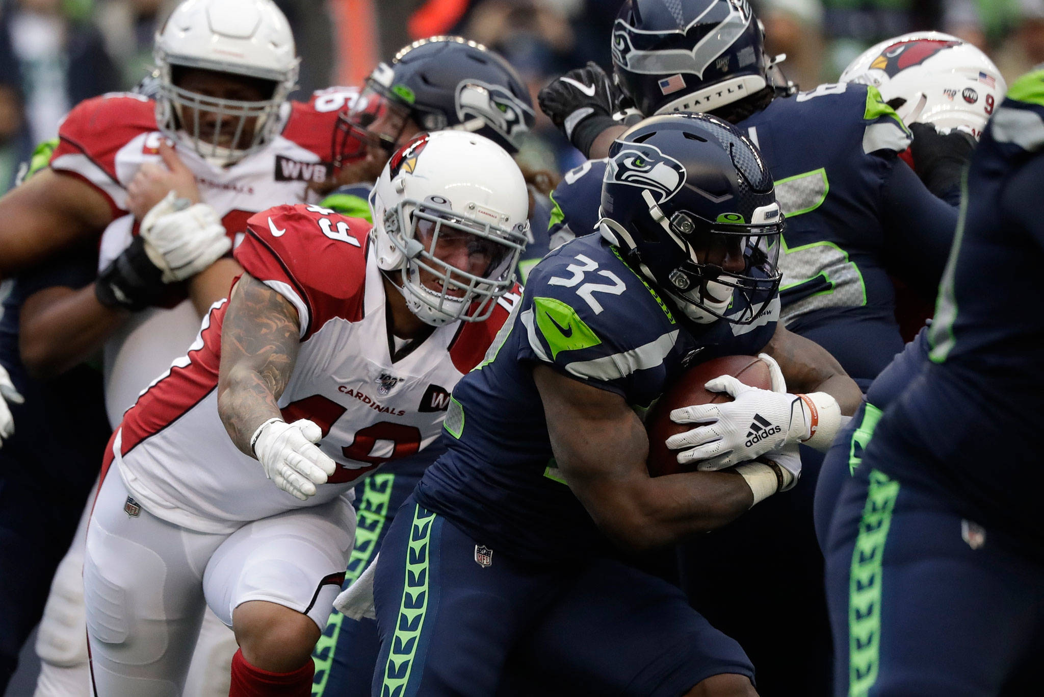 Seahawks running back Chris Carson (32) rushes past Cardinals defenders during the first half of a game Dec. 22, 2019, in Seattle. (AP Photo/Elaine Thompson)