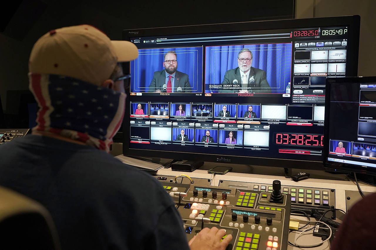 A technician works in a TVW control room during Thursday’s debate in Olympia between U.S. Rep. Denny Heck (shown at right on the video monitor) and Washington Sen. Marko Liias (left) in the race for lieutenant governor of Washington state. (AP Photo/Ted S. Warren)