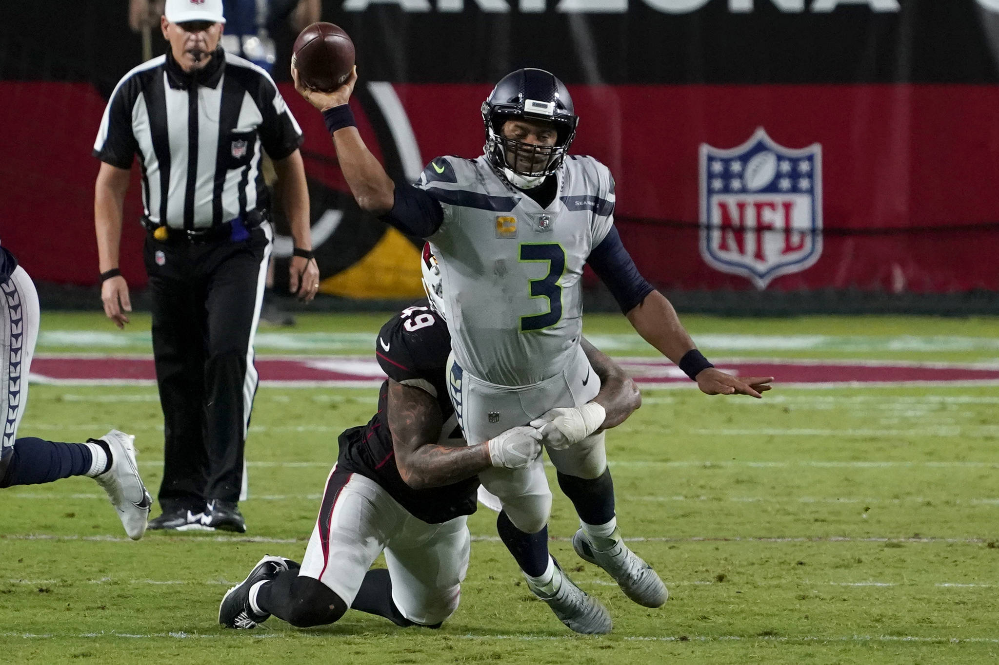 Seattle Seahawks quarterback Russell Wilson (3) gets the throw off as Arizona Cardinals linebacker Kylie Fitts makes the hit during the second half of Seattle’s 37-34 overtime loss Sunday at State Farm Stadium. (AP Photo/Rick Scuteri)