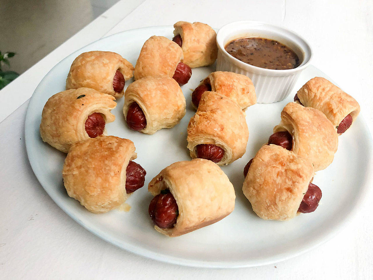For these upscale pigs in a blanket, Chef Alex Guarnaschelli tucks chopped parsley into the pastry and adds tabasco and grainy mustard to the sauce. (Kate Krader / Bloomberg)