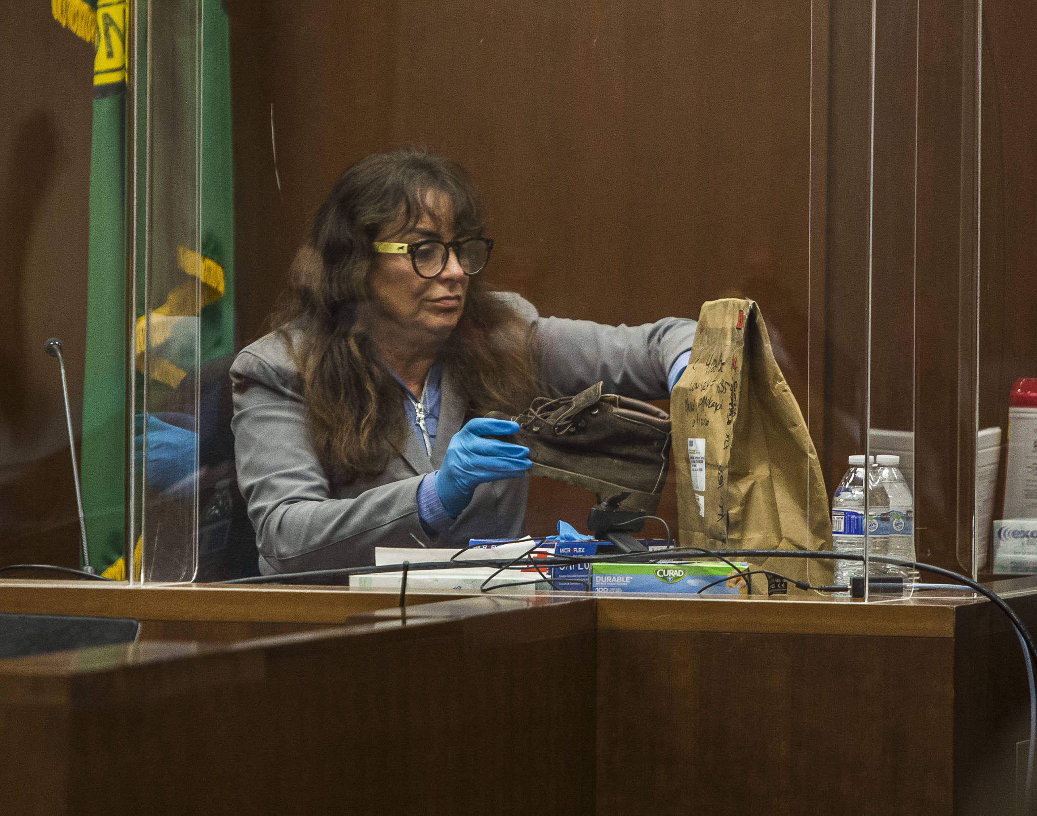 Jana Smith places the boot worn by her sister, Jody Loomis, back into an evidence bag while testifying Wednesday in Everett. (Olivia Vanni / The Herald)