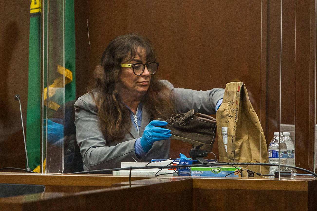 Jana Smith places her sister Jody Loomis' boot back into an evidence bag while testify on Wednesday, Oct. 28, 2020 in Everett, Wa. (Olivia Vanni / The Herald)