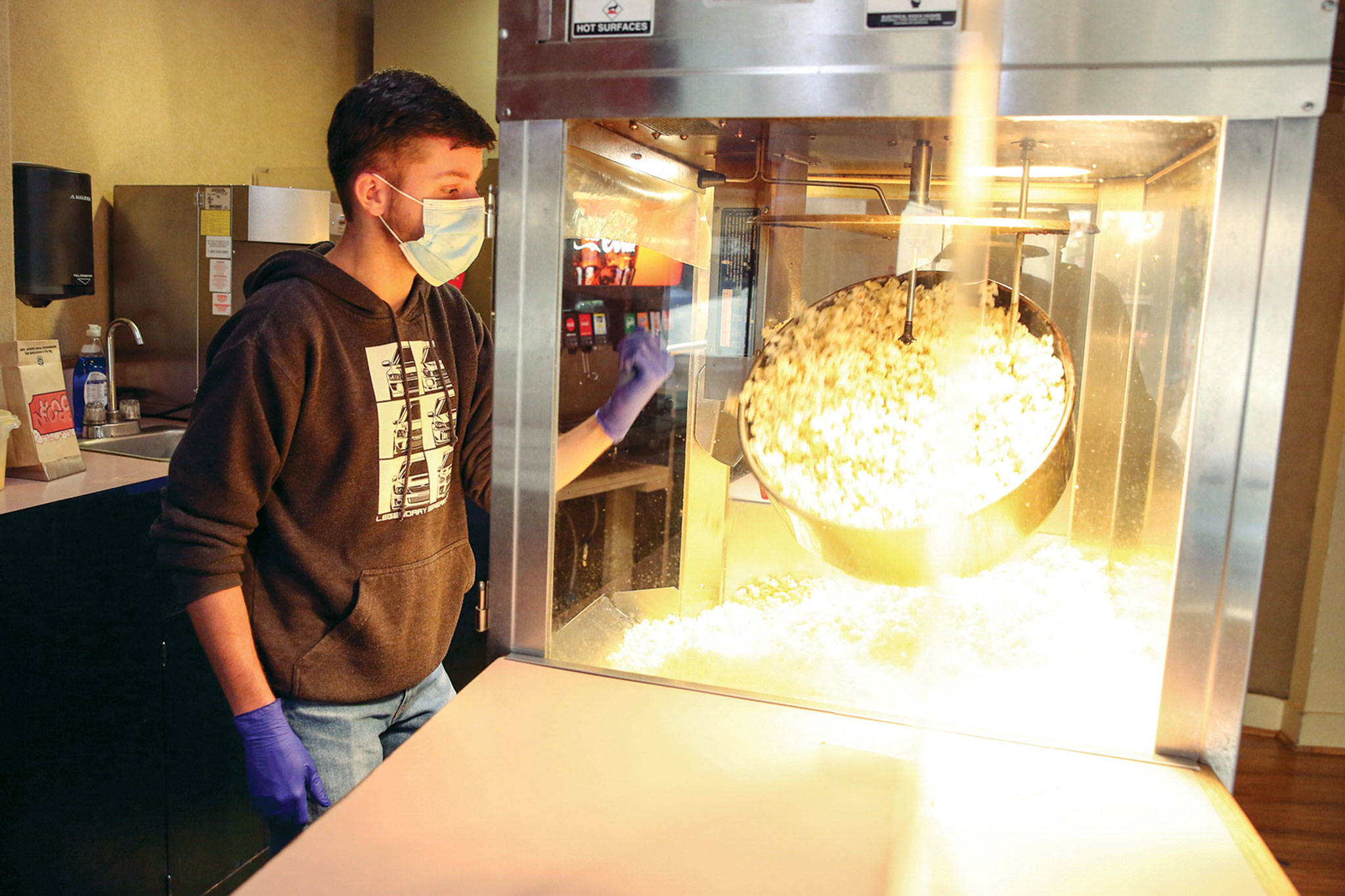 Jack Eccleshall makes popcorn at the theater for sale while it was still closed. (Kevin Clark / The Herald)