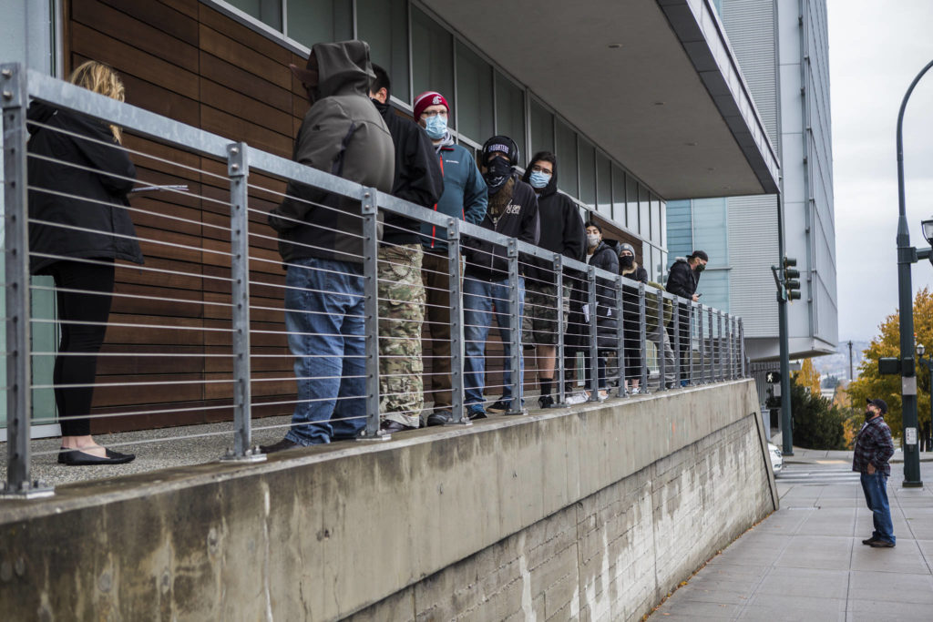 People line up outside of the County Public Meeting Room to turn in ballots, register to vote and get help on Tuesday in Everett. (Olivia Vanni / The Herald) 
