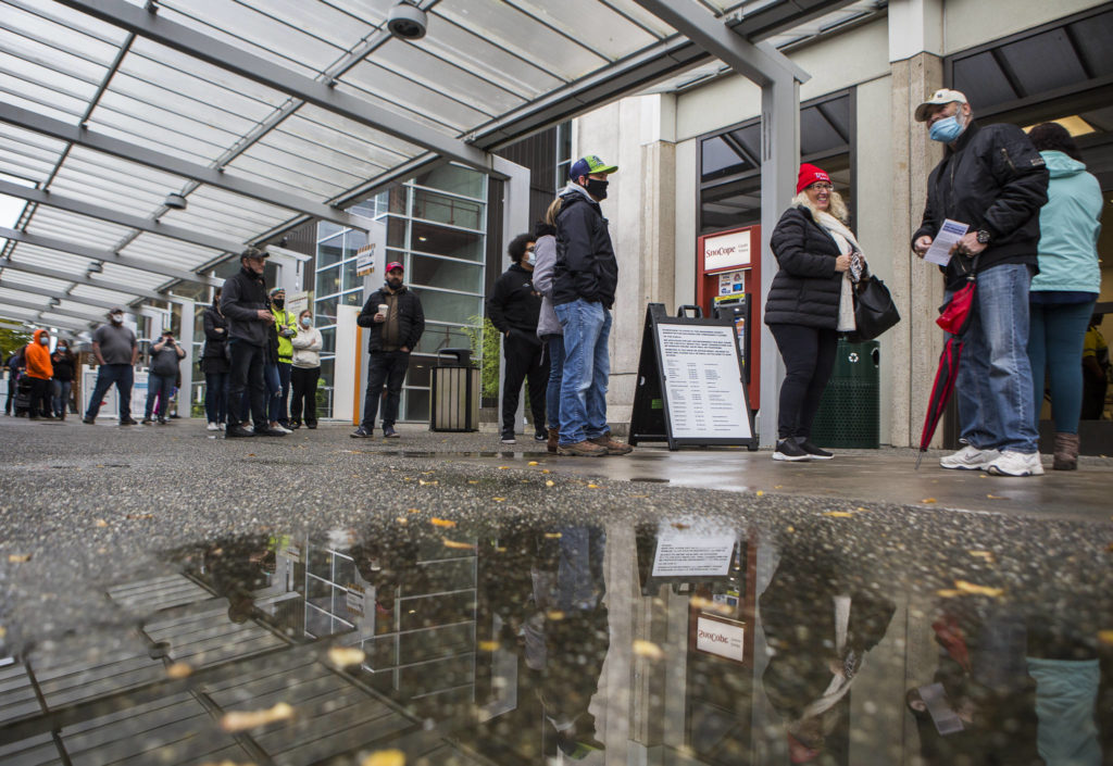 People wait in line outside the Snohomish County auditor’s office to turn in ballots, register to vote and get help on Tuesday in Everett. (Olivia Vanni / The Herald) 
