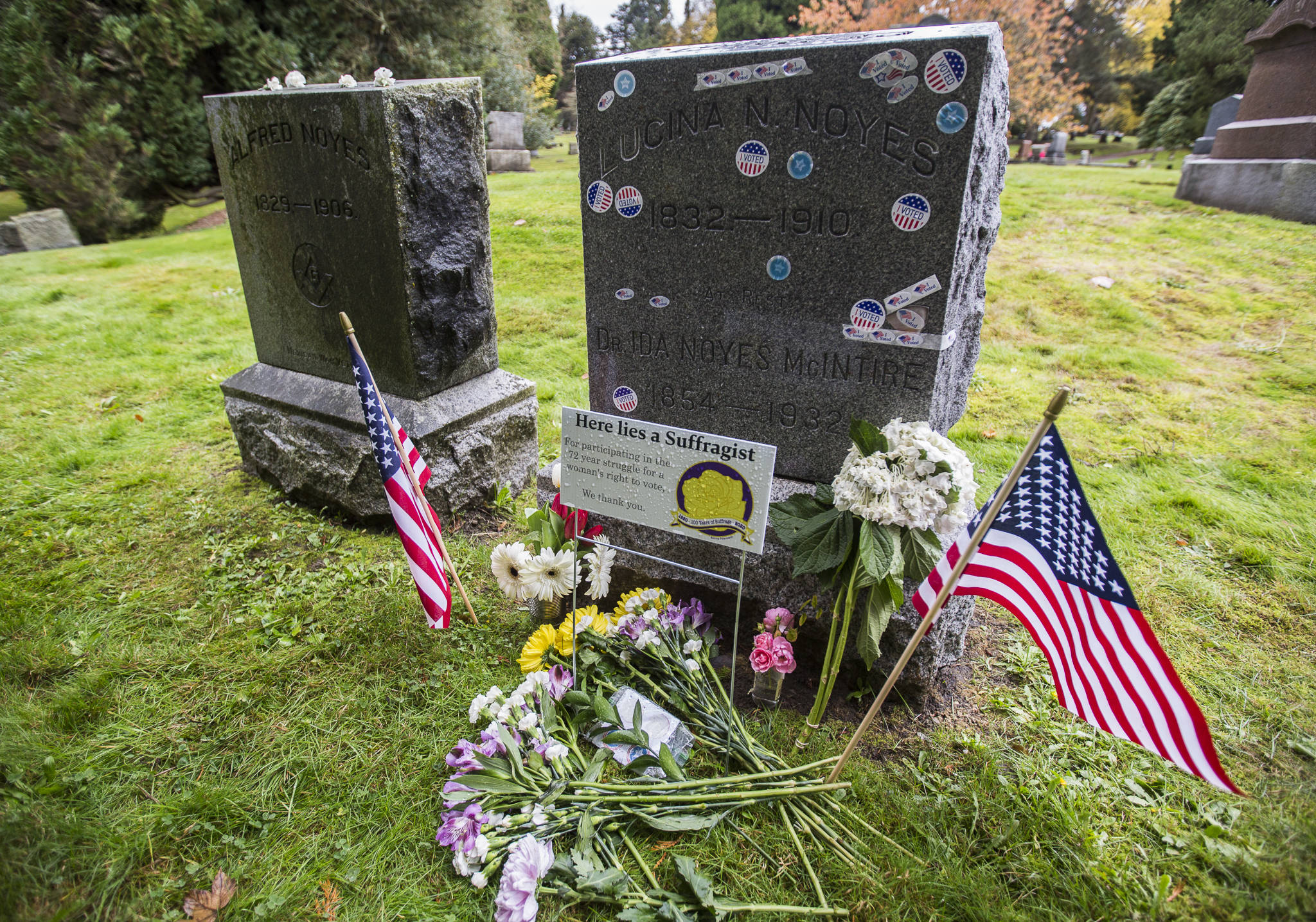 The gravesite of Dr. Ida Noyes McIntire, a suffragist, is surrounded by flowers and covered in “I Voted” stickers at Evergreen Cemetery on Wednesday in Everett. (Olivia Vanni / The Herald)
