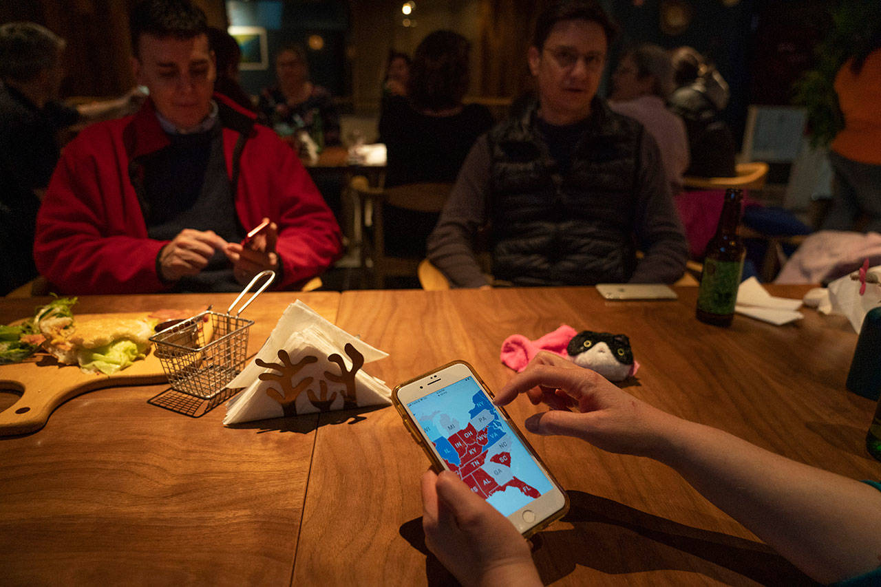 Expatriates monitor electoral maps on their mobile phones during an election watch event held by Democrats Abroad at a restaurant in Beijing, China on Nov. 4. (Ng Han Guan / Associated Press)