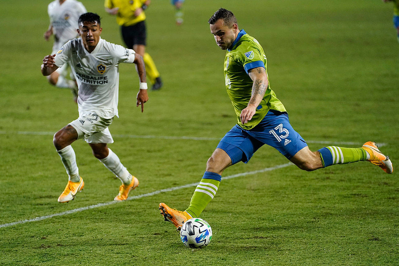 Seattle Sounders forward Jordan Morris, right, takes a shot in front of LA Galaxy defender Julian Araujo during the first half of an MLS soccer match Wednesday, Nov. 4, 2020, in Carson, Calif. (AP Photo/Ashley Landis)