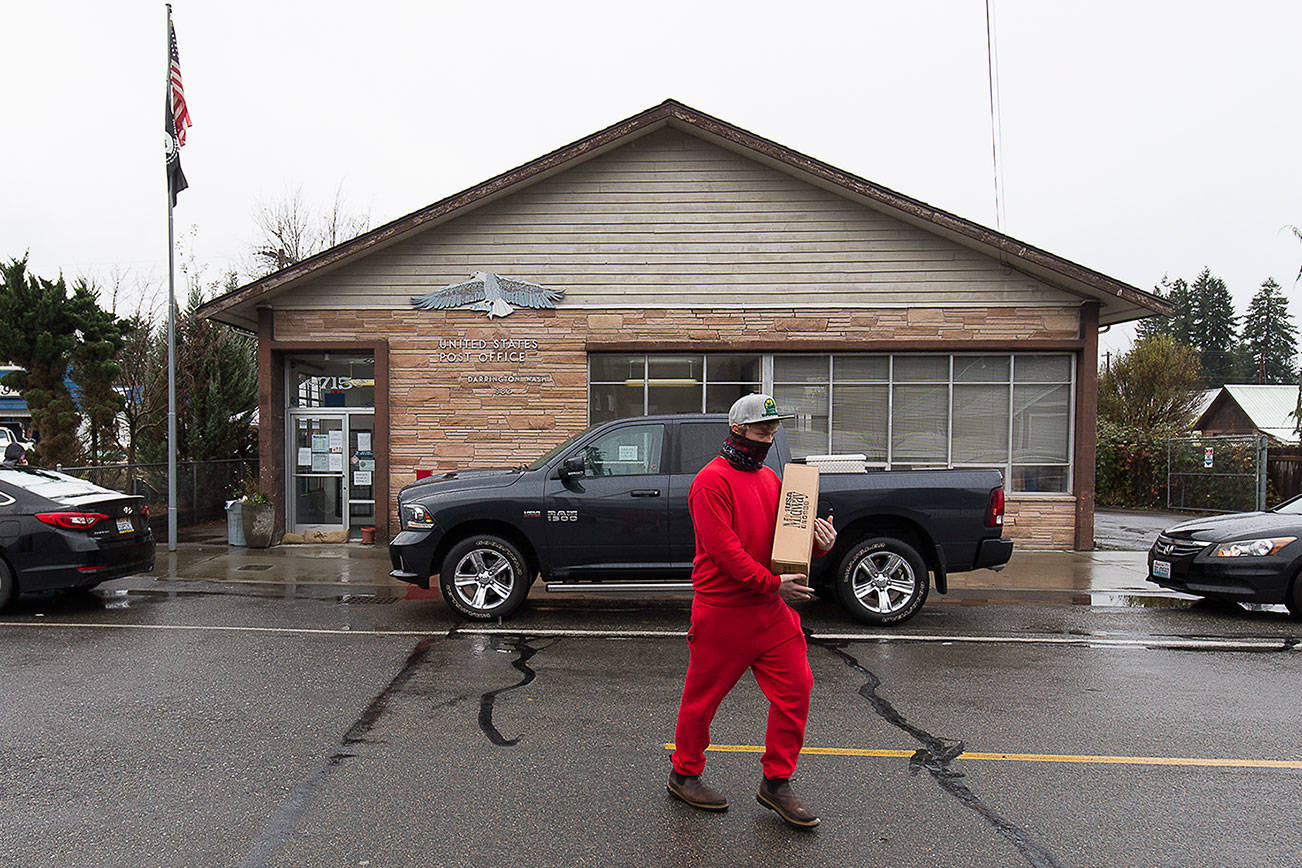 Dustin Grant carries a package after picking it up outside the closed Darrington Post Office on Tuesday, Nov. 10, 2020 in Darrington, Washington.  (Andy Bronson / The Herald)