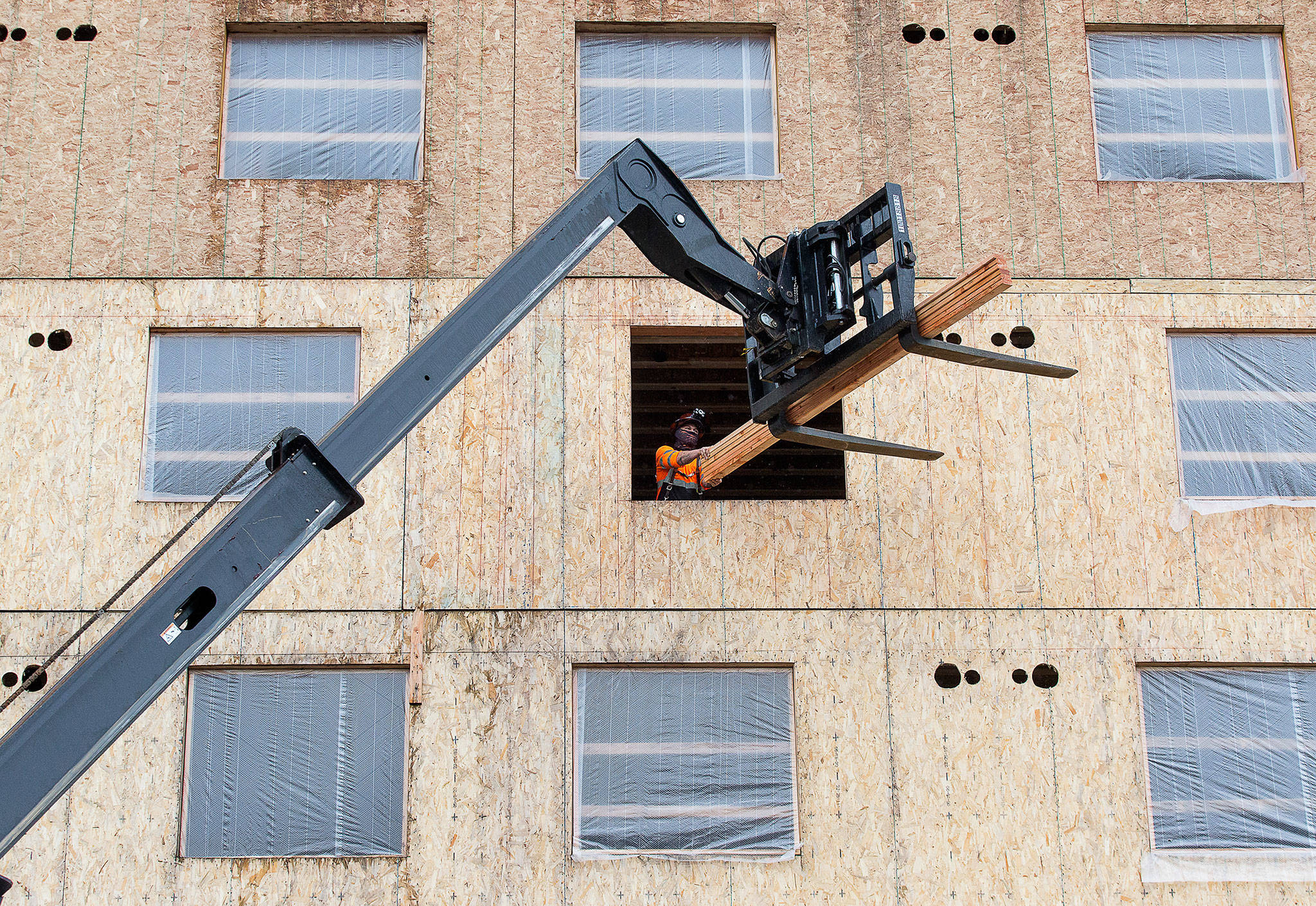 A worker unloads two-by-fours from a forklift as construction continues on the new Compass Health project on 33rd Street on Nov. 18 in Everett. (Andy Bronson / The Herald)