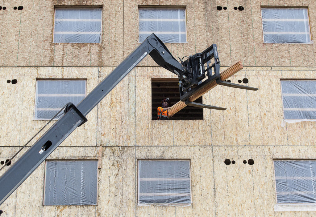 A worker unloads two-by-fours from a forklift as construction continues on the new Compass Health project on 33rd Street on Nov. 18 in Everett. (Andy Bronson / The Herald)
