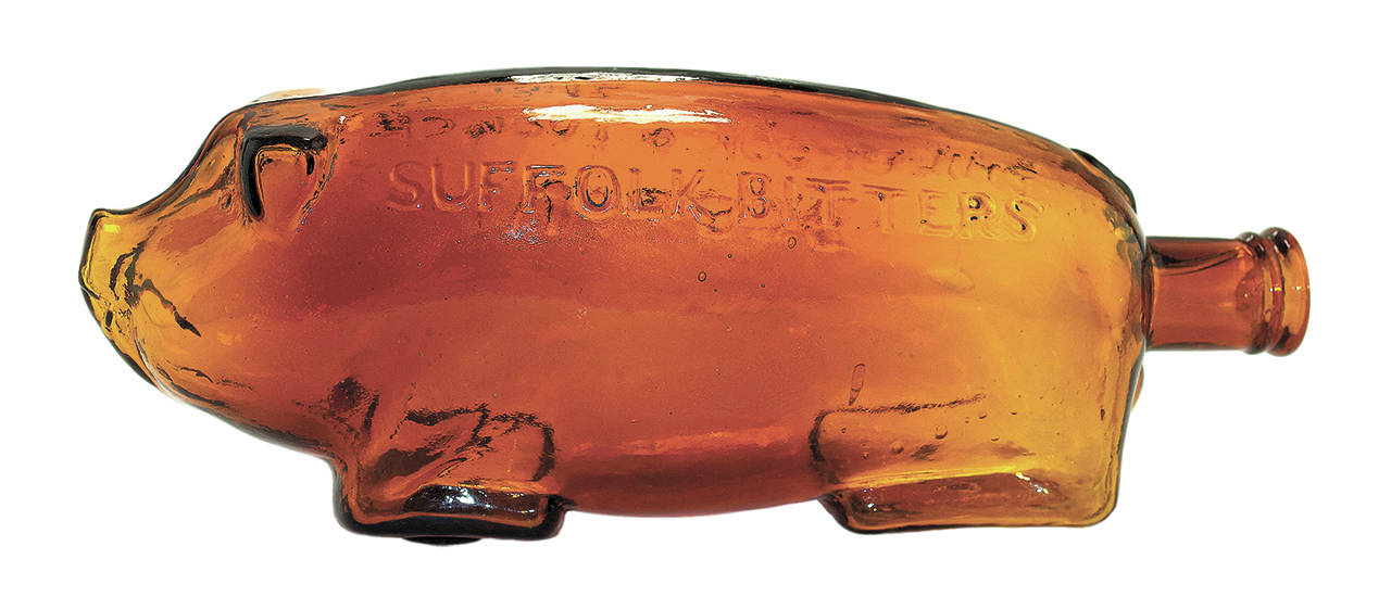 There have been copies of the antique Suffolk pig bottles in other colors of glass. The original bottle is 10 inches long and has a smooth base. (Cowles Syndicate Inc.)