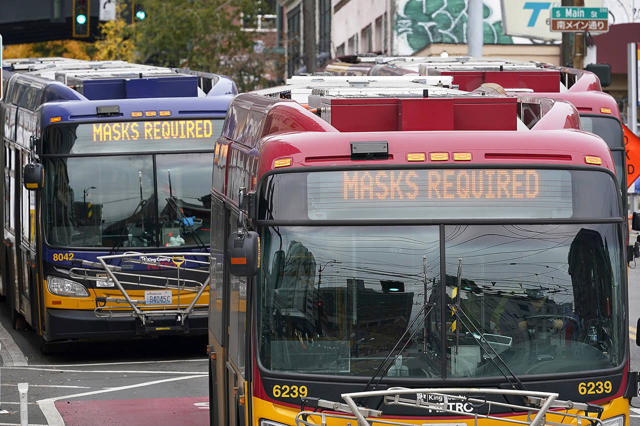 Metro buses post signs advising that masks are required Thursday in Seattle. (AP Photo/Elaine Thompson)