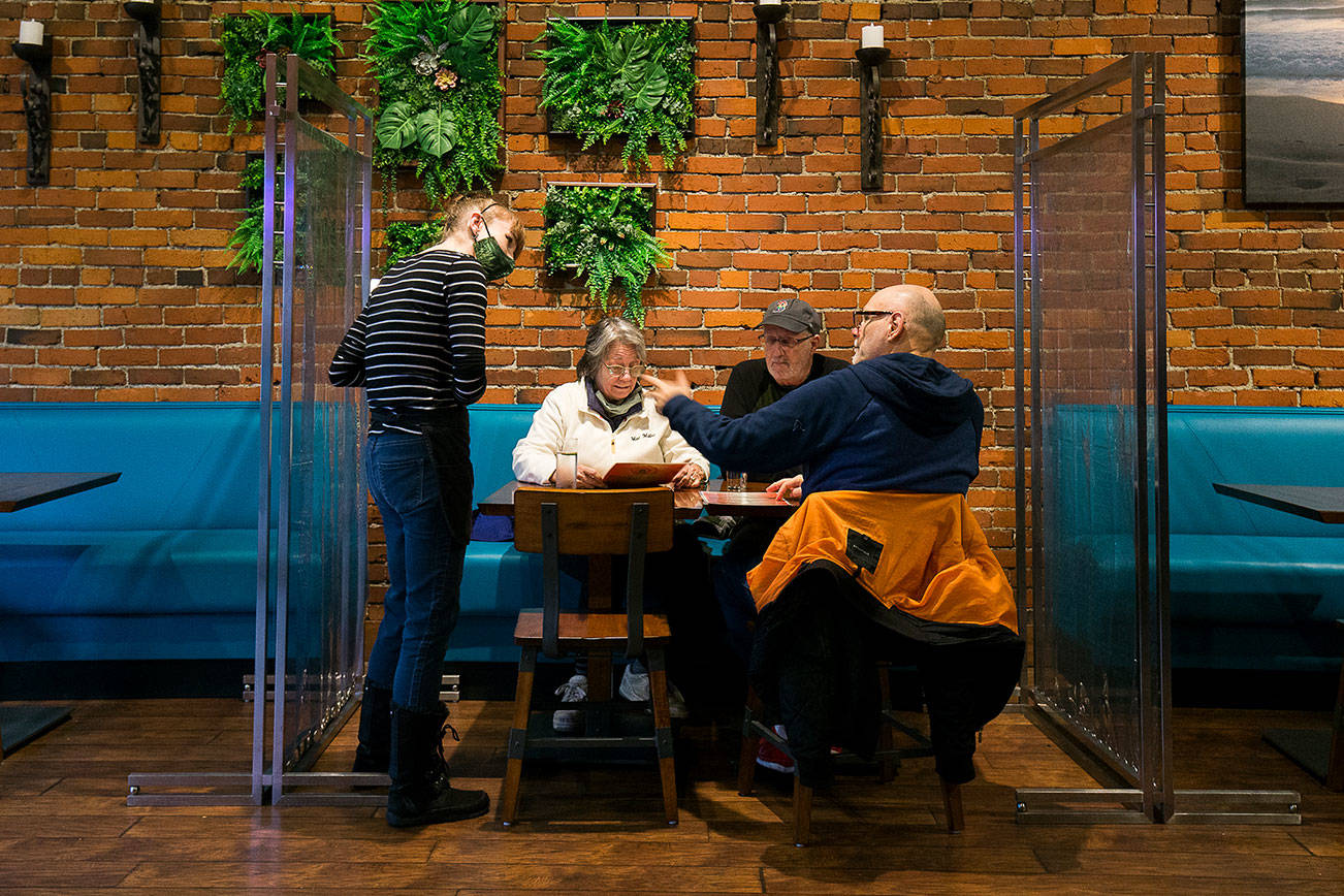 Server Kelly King talks with diners Suzan Nettleship, Bill Zama and Rodger Scheibner as they enjoy a last meal inside, before restrictions take place, at Sol Food on Monday, Nov. 16, 2020 in Everett, Washington.  (Andy Bronson / The Herald)