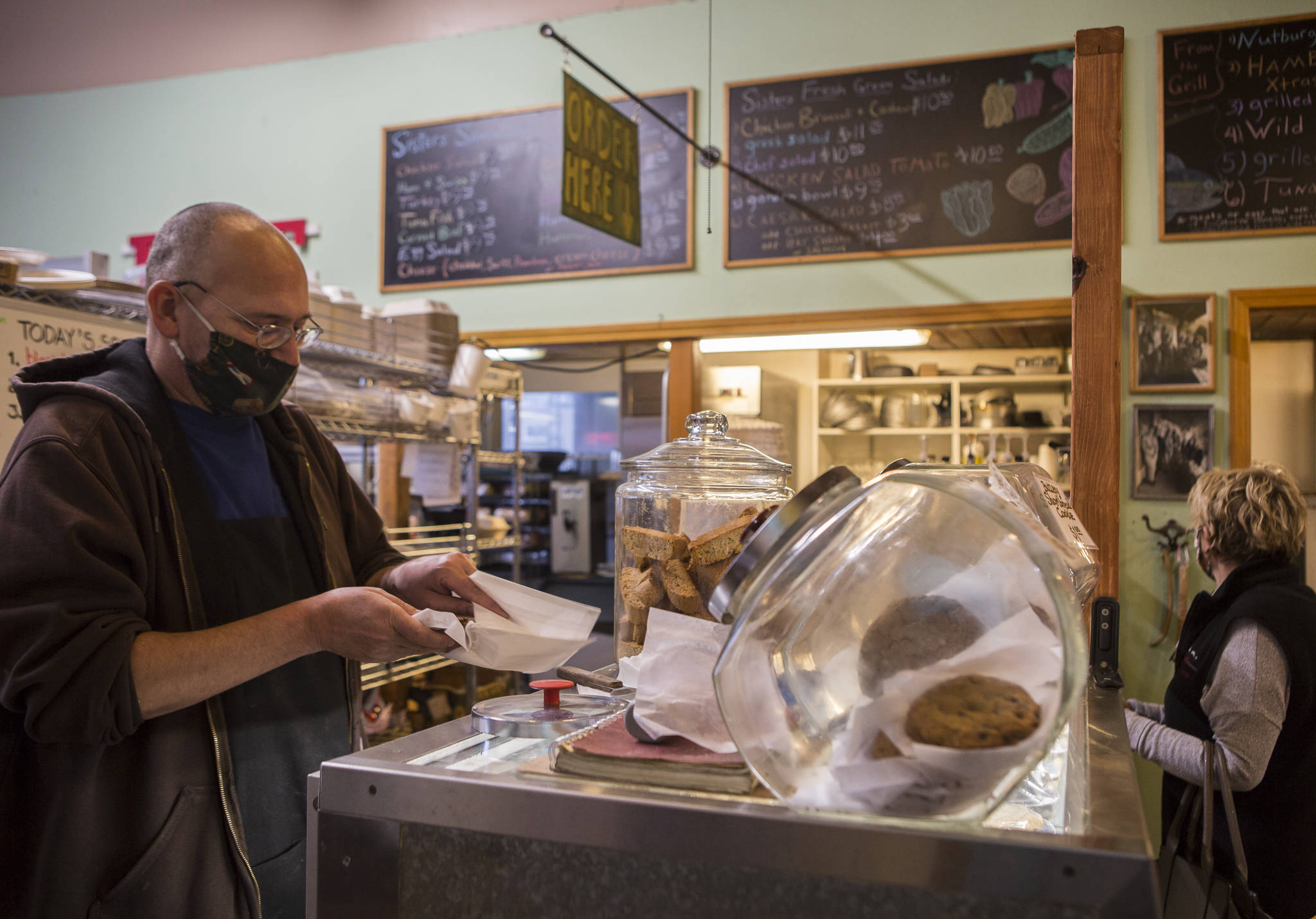 Burton Clemans, an employee at Sisters for 8 years, packages up a cookie on Tuesday in Everett. (Olivia Vanni / The Herald)