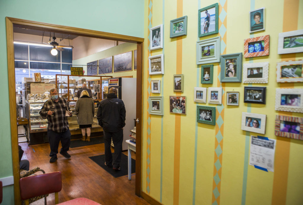 Customers stand in line for orders next to a wall of family photographs at Sisters on Tuesday in Everett. (Olivia Vanni / The Herald)
