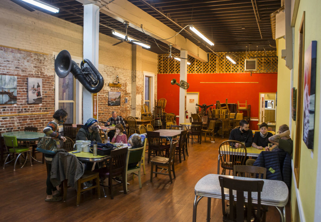 Customers sit socially distanced at tables inside Sisters on Tuesday in Everett. (Olivia Vanni / The Herald)
