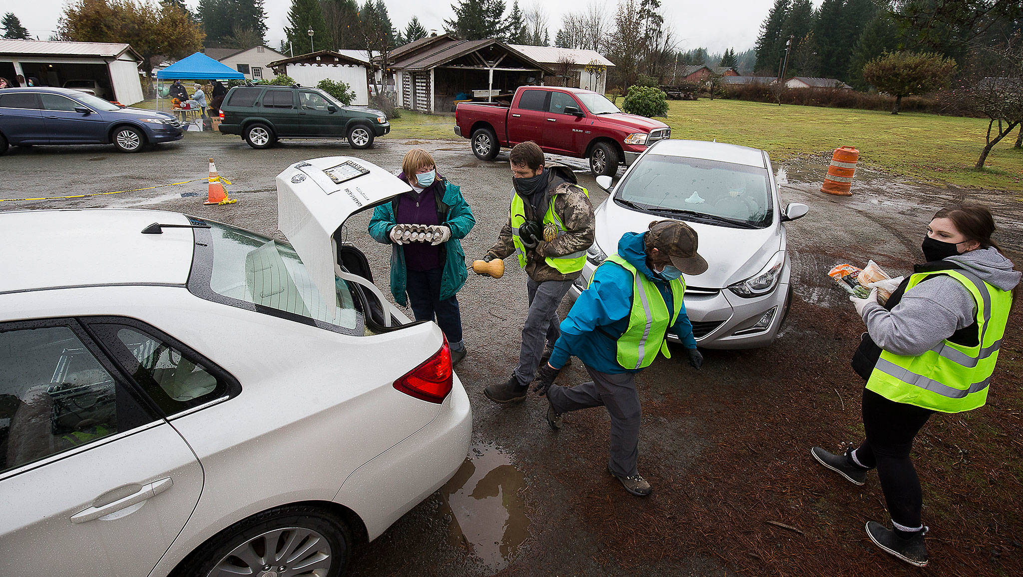 Volunteers load a car with food during a drive-through event for families in need called the “Colors of Fall” at the Darrington Food Bank on Monday, Nov. 23, 2020 in Darrington, Washington. Stops along the drive-thru provided hand sanitizer, masks, food boxes, assistance information for those that need help with early learning, utilities, mental health, etc.  (Andy Bronson / The Herald)
