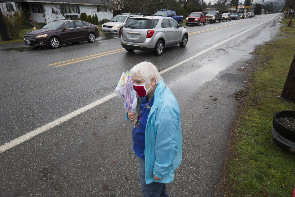 North County Family Services volunteer Mary Requa waits to hand out surveys for drivers waiting in line for a drive-through event for families in need called the “Colors of Fall” at the Darrington Food Bank on Monday. (Andy Bronson / The Herald)
