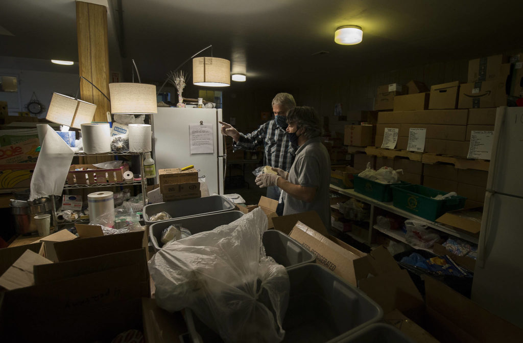 Hugh Kahn and Steve Brown (right) organize frozen items for a drive-through event for families in need called the “Colors of Fall” at the Darrington Food Bank on Monday. (Andy Bronson / The Herald)
