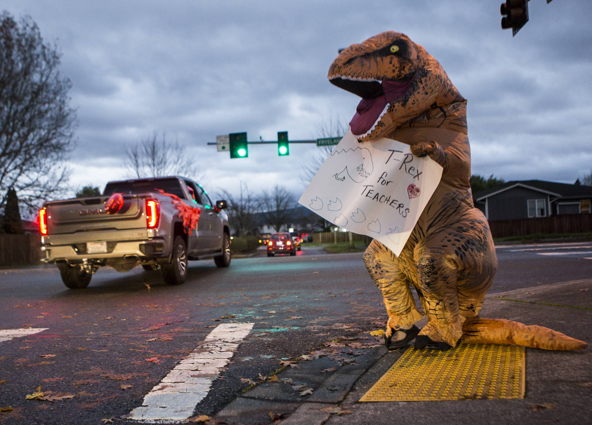 Costumed Sky Valley Education Center teacher Jeanna Stroble waves a sign in support of a parade and celebration on Thursday in Monroe, where first-grade teachers opposed a school district move to resume in-class learning. That decision was rescinded. (Olivia Vanni / The Herald)