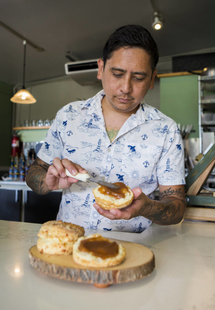 Biscuit Bean chef-owner Ben Libay spreads apple butter on a buttermilk biscuit at the Lake Stevens store. (Olivia Vanni / The Herald)
