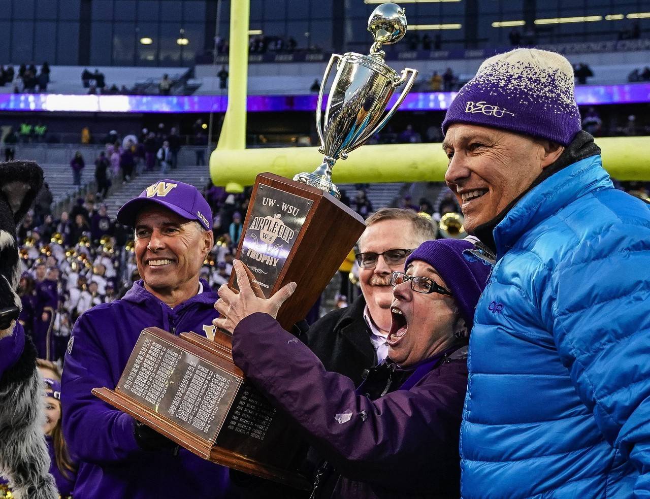 Washington Governor Jay Inslee, right, hands off the Apple Cup Trophy to University of Washington president Ana Mari Cauce and Huskies head coach Chris Petersen, left, last year at Husky Stadium. (Dean Rutz | Seattle Times/TNS)