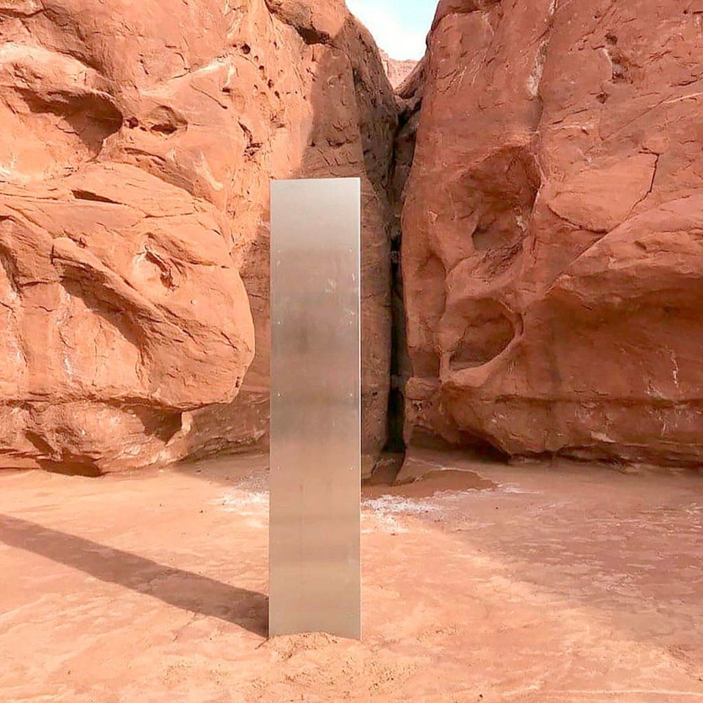 A Utah state worker stands next to a metal monolith in the ground in a remote area of red rock Nov. 18 in Utah. The Bureau of Land Management said it had received credible reports that the three-sided stainless steel structure was removed on Nov. 27. (Utah Department of Public Safety via AP, File)
