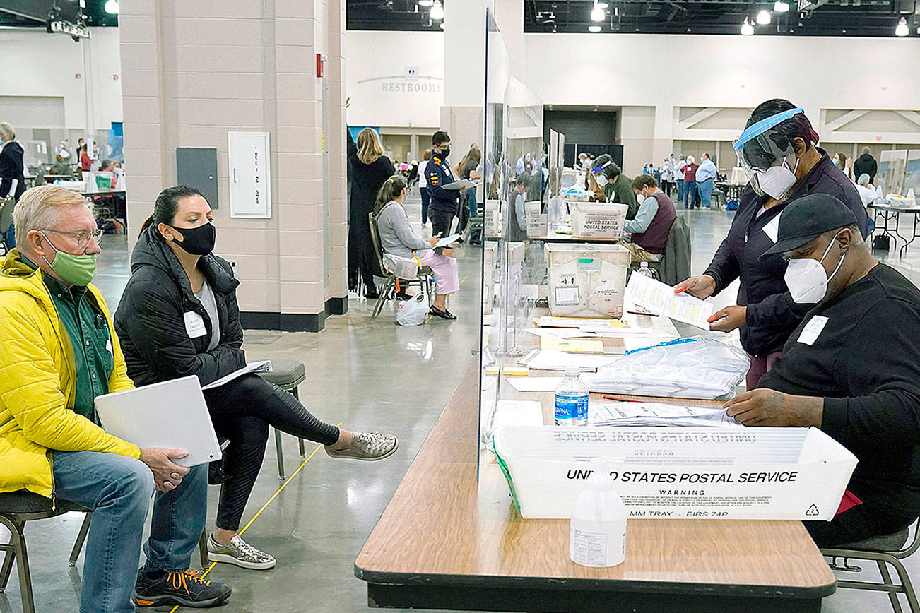 FILE - Election workers, right, verify ballots as recount observers, left, watch during a Milwaukee hand recount of presidential votes at the Wisconsin Center, Friday, Nov. 20, 2020, in Milwaukee. Wisconsin finished a partial recount of its presidential results on Sunday, Nov. 29, 2020 confirming Democrat Joe Biden's victory over President Donald Trump in the key battleground state. Trump vowed to challenge the outcome in court. (AP Photo/Nam Y. Huh)