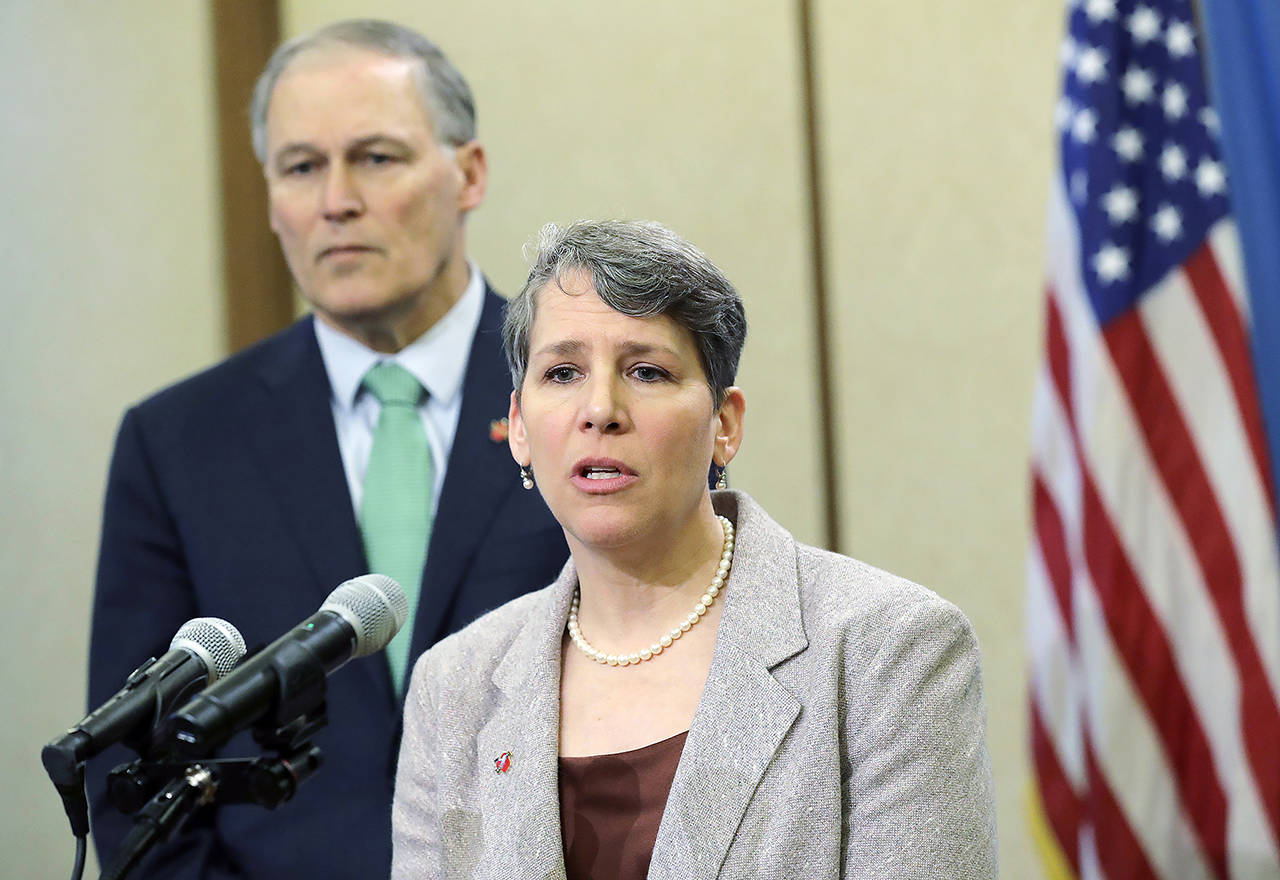 In this January 2019 photo, Washington Gov. Jay Inslee looks on as Suzi LeVine, the state’s Employment Security Department Commissioner, talks to reporters at the Capitol in Olympia. (AP Photo/Ted S. Warren, File)