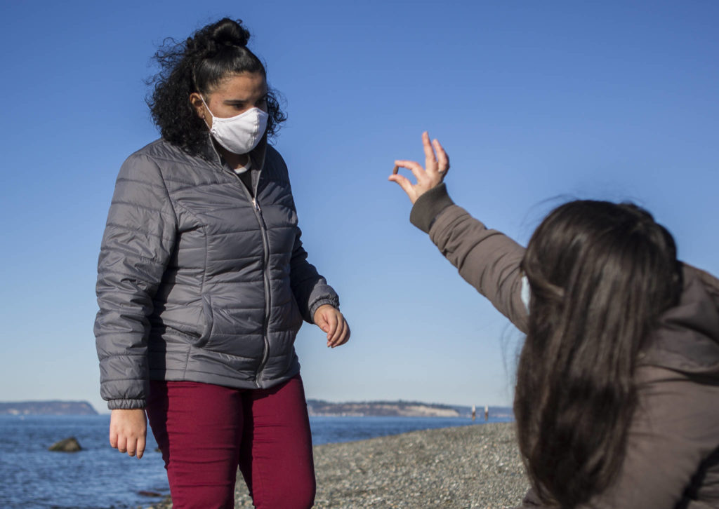 Jessica Parsons and Aliyah Velasquez look at shells and rocks along Mukilteo Beach on Dec. 2. (Olivia Vanni / The Herald)
