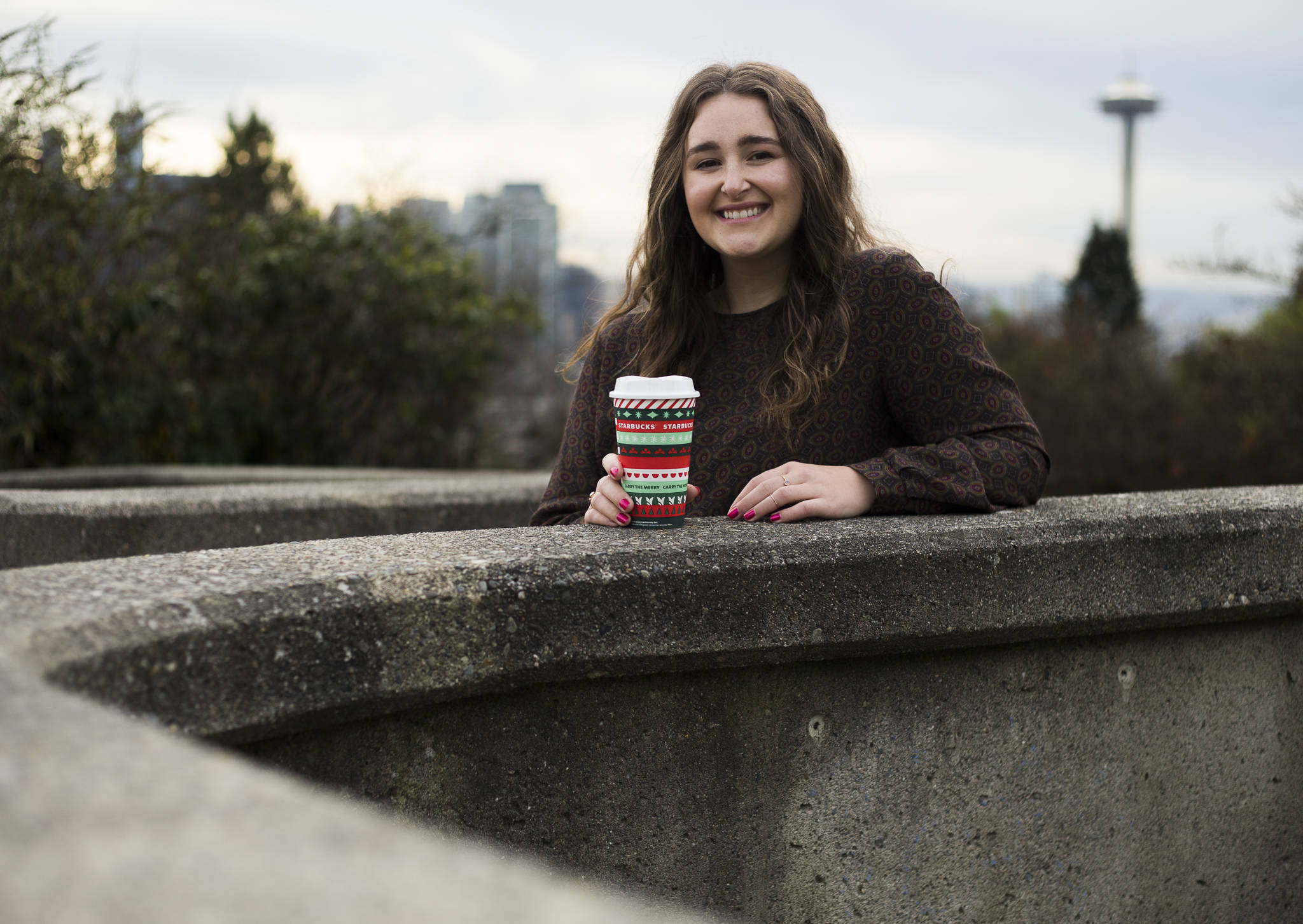 Taylor Mattson, 27, who grew up in Everett, holds the “Ribbon” Starbucks red cup she designed that evokes a holiday sweater type pattern. The cup is used worldwide. (Olivia Vanni / The Herald)