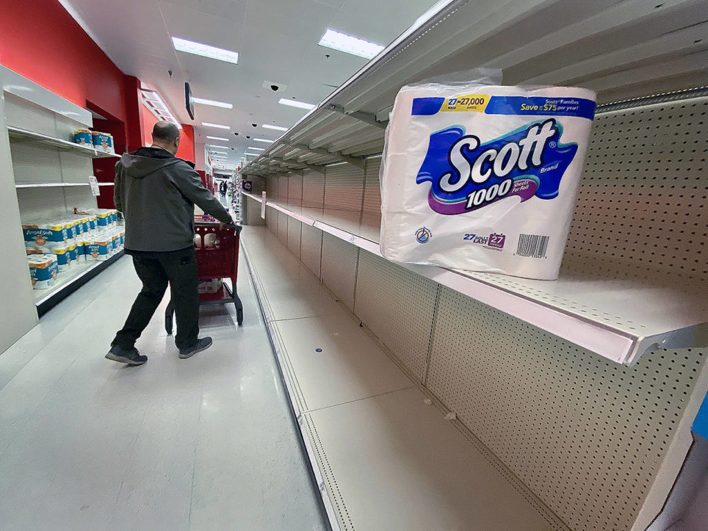 A supersized package of toilet paper is returned to the empty shelf at the Lynnwood Target in March 2020. (Andrea Brown/The Herald)
