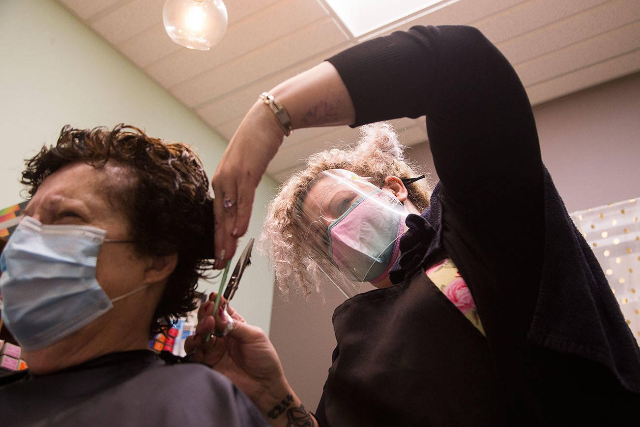 Wearing a mask and face shield, Honeycomb Salon owner Julia Barbee, styles Gail Linnick's hair in her studio at Sola Studios, on Wednesday, Dec. 16, 2020 in Mill Creek, Wa.(Andy Bronson / The Herald)