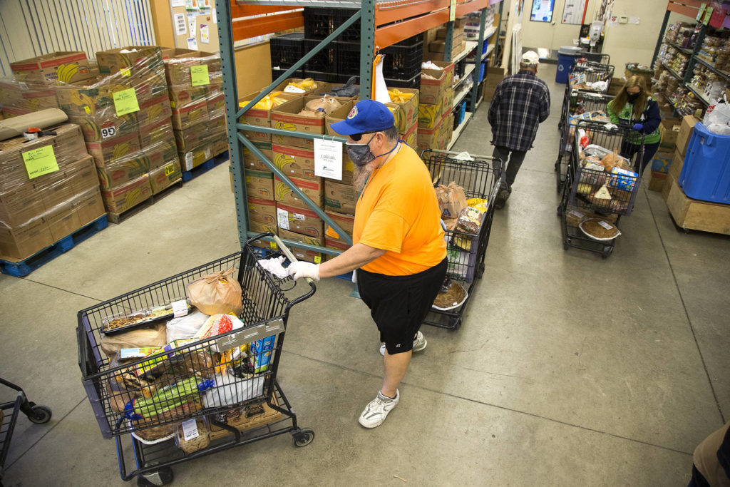 Volunteer Kevin Boldt and Jennifer Chapman direct shopping carts full of food outside at the Marysville Community Food Bank on Nov. 30. (Andy Bronson / The Herald)
