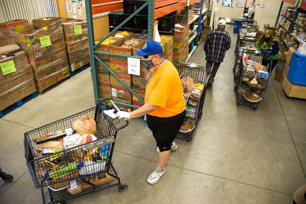 Volunteer Kevin Boldt and Jennifer Chapman direct shopping carts full of food outside at the Marysville Community Food Bank on Monday, Nov. 30, 2020 in Marysville, Washington.  (Andy Bronson / The Herald)