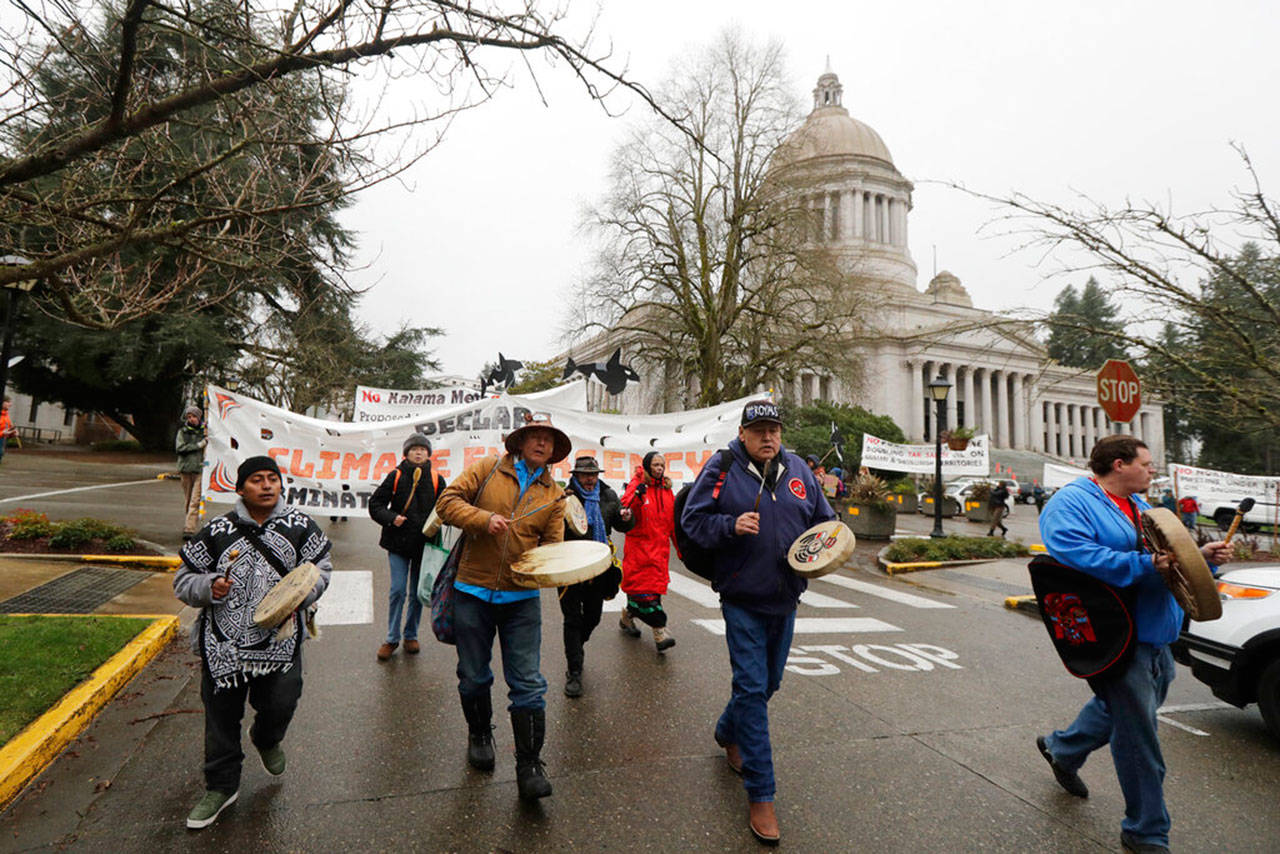 Climate activists and others supporting the Indigenous group “Protectors of the Salish Sea” march with signs and drums outside the Capitol at Olympia, Wash., Monday, Jan. 13, in Olympia, on the first day of the 2020 session of the Washington legislature. The group was at the Capitol to call attention to environmental issues including their demand that Gov. Jay Inslee declare a climate emergency and halt fossil fuel expansion projects in the state. (Ted S. Warren / Associated Press file photo)