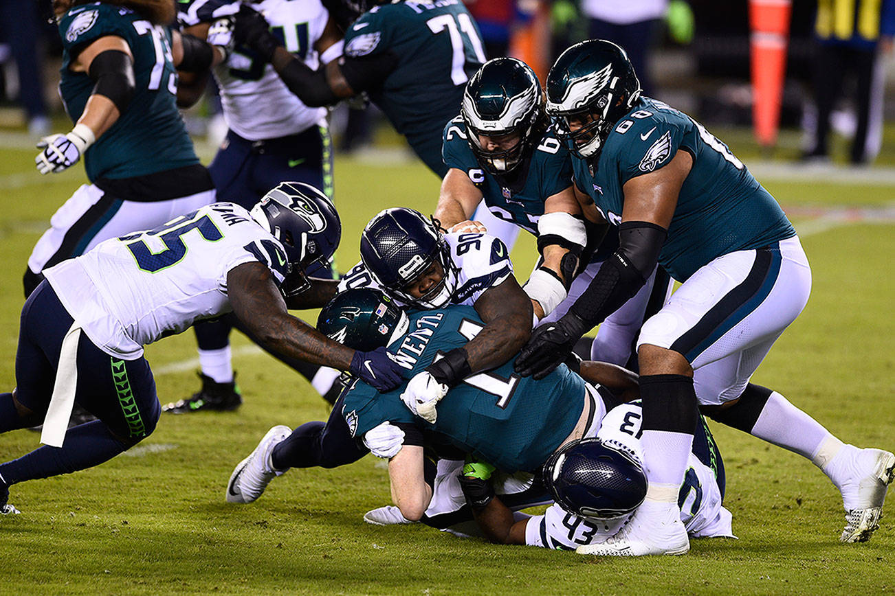 Philadelphia Eagles' Carson Wentz (11) is tackled by Seattle Seahawks' Carlos Dunlap (43), Jarran Reed (90) and Benson Mayowa (95) during the first half of an NFL football game, Monday, Nov. 30, 2020, in Philadelphia. (AP Photo/Derik Hamilton)