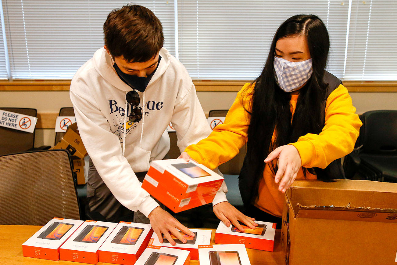 Ian McKnight (left) and Nhu Nguyen sort purchased and donated devices for Telehealth Access for Seniors Friday afternoon in Everett on December 4, 2020.  (Kevin Clark / The Herald)