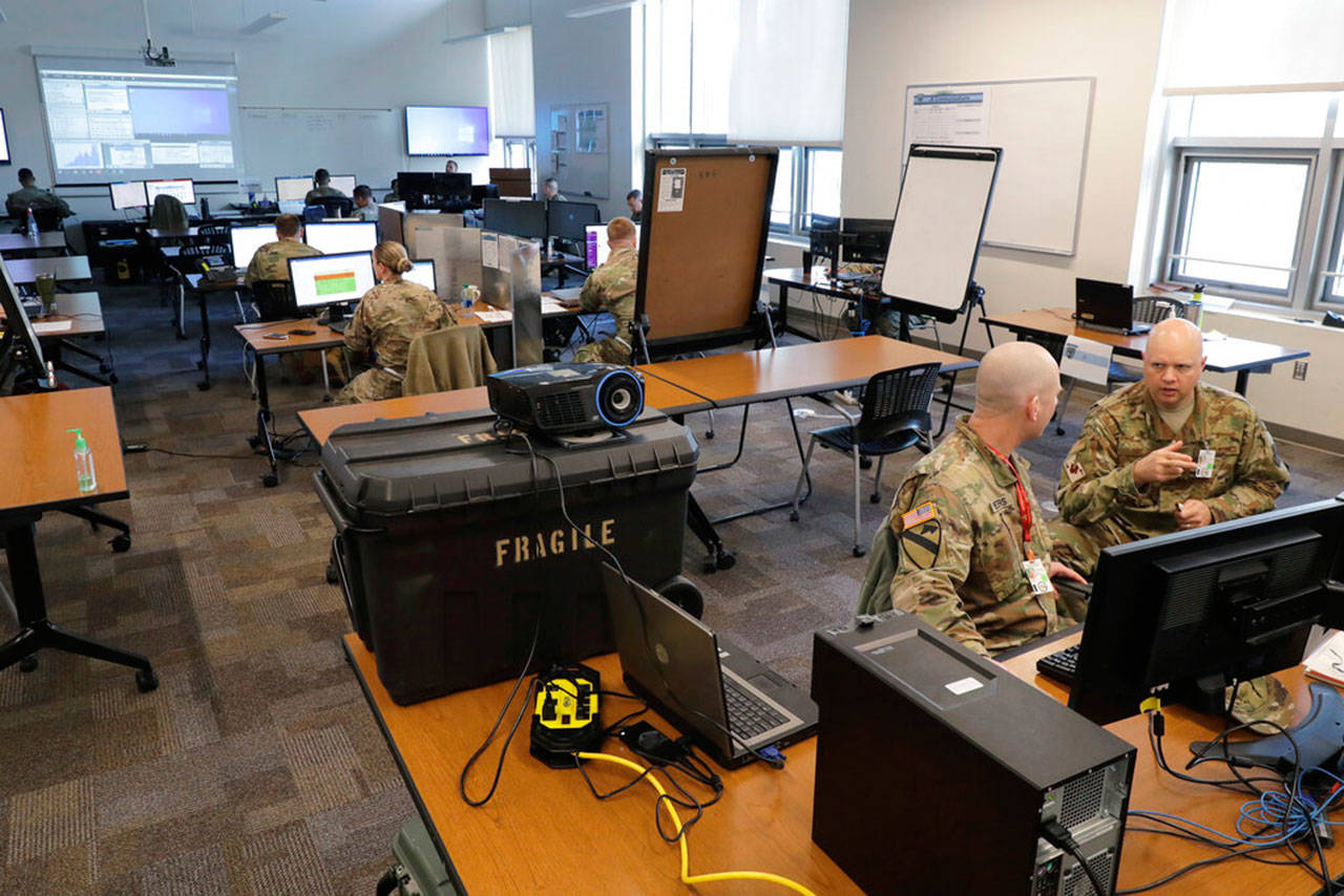 Washington Army and Air National Guard soldiers confer in an operations room at Camp Murray in May. The state of Washington called in the National Guard to help process unemployment benefit claims as officials grappled with a backlog caused in part by a fraud ring that stole more than half a billion dollars in jobless aid. (Ted S. Warren / Associated Press file photo)