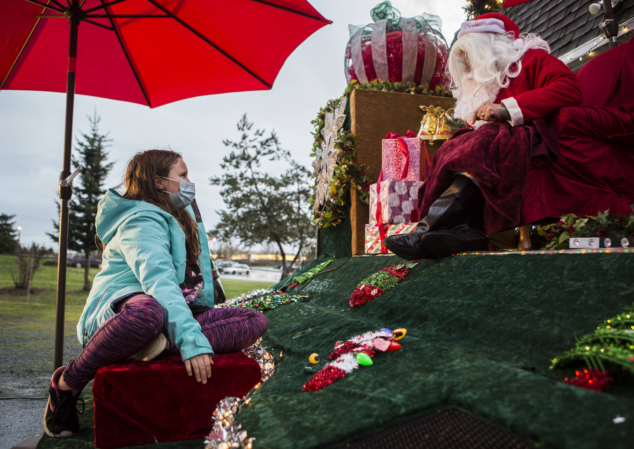 Callie Fosie, 11, talks to Santa Claus about seeing him in her house a few Christmases ago. They spoke during the socially distanced meet-up hosted by Maryfest on Thursday in Marysville. (Olivia Vanni / The Herald)