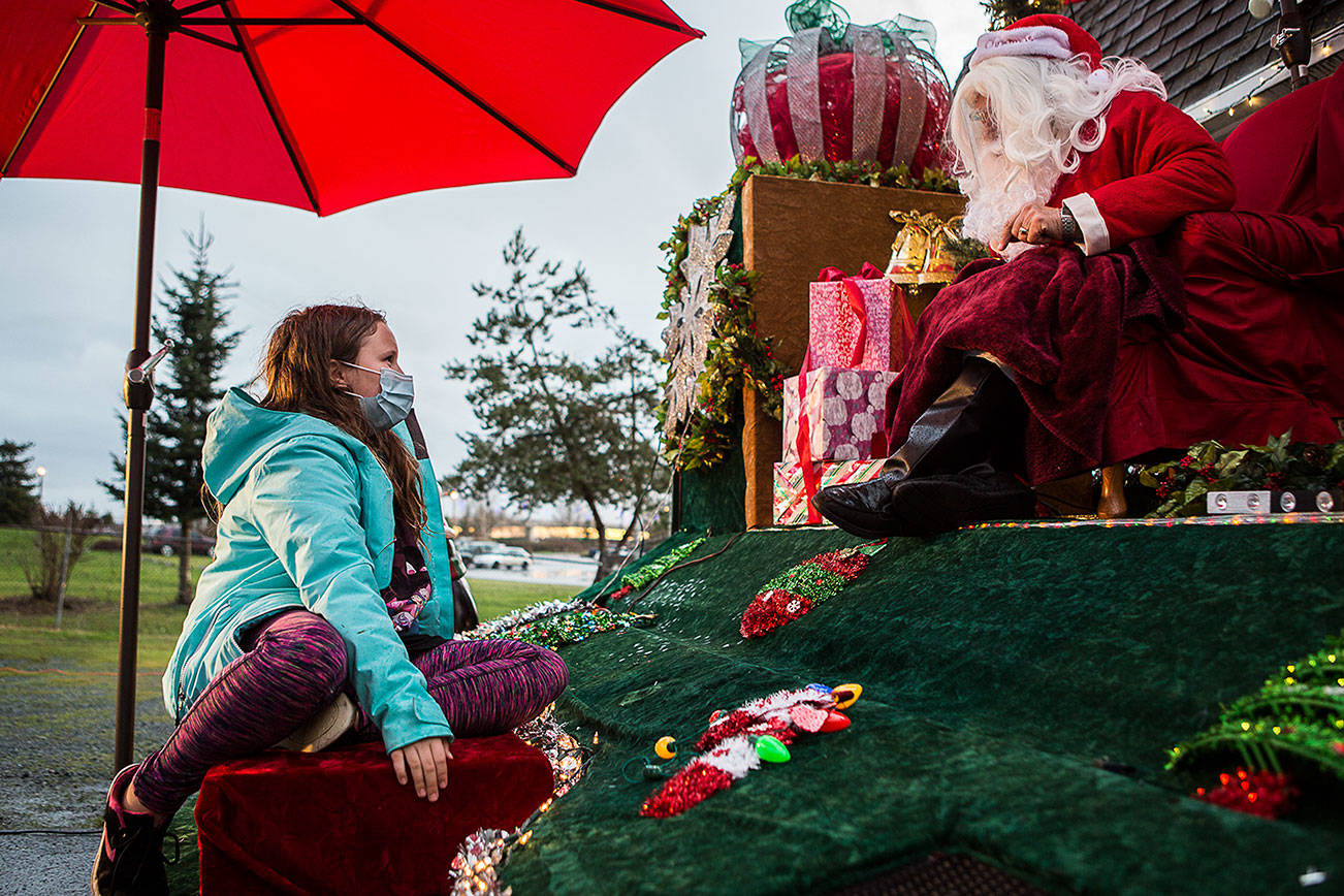 Callie Fosie, 11, talks to Santa Claus about seeing him in her house a few Christmases ago during the socially distanced meet up hosted by Maryfest on Thursday, Dec. 17, 2020 in Marysville, Wa. (Olivia Vanni / The Herald)