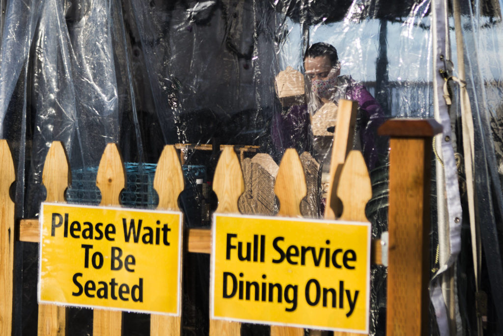 A waiter at Ivar’s packages food to go inside the outdoor tent in Mukilteo on Wednesday. (Olivia Vanni / The Herald)
