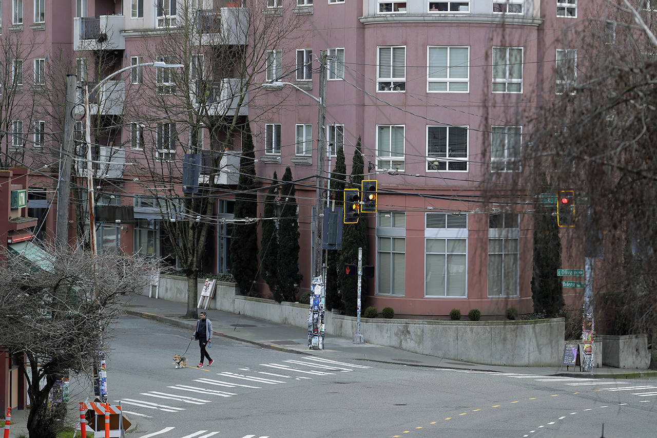 A man walks a dog March 24 near apartments in Seattle’s Capitol Hill neighborhood. (AP Photo/Ted S. Warren, file)