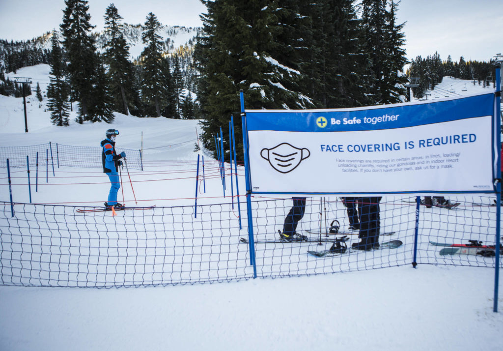 A socially distanced and masked, a skier waits in line for lifts to open at Stevens Pass last Friday. (Olivia Vanni / The Herald)
